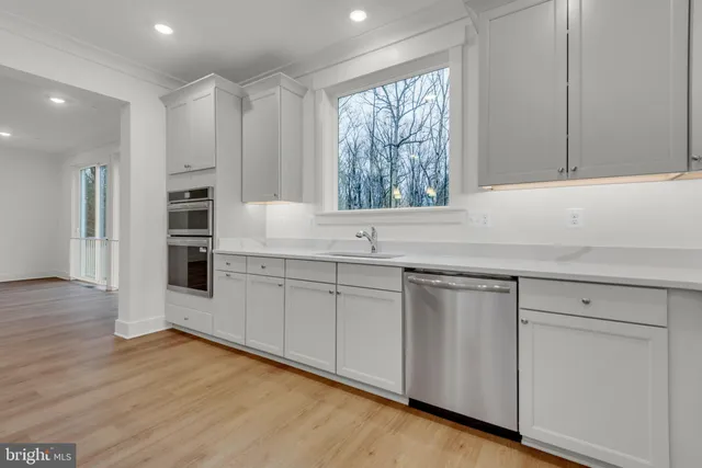 a kitchen with stainless steel appliances granite countertop a refrigerator a sink dishwasher and a oven with white cabinets