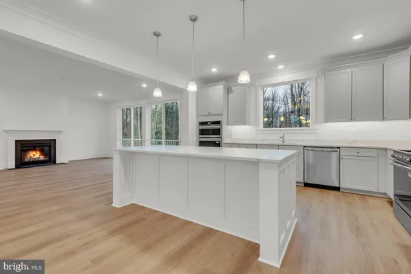 a kitchen with stainless steel appliances granite countertop a refrigerator a sink a stove and white cabinets with wooden floor