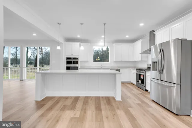 a large kitchen with stainless steel appliances kitchen island a large counter top and wooden floors