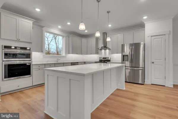 a view of a kitchen and an empty room with wooden floor