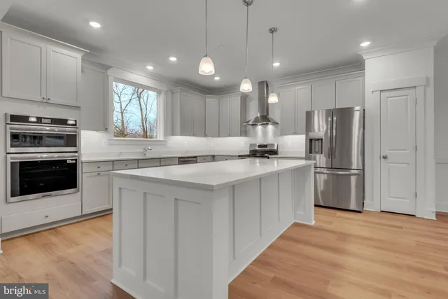 a view of a kitchen and an empty room with wooden floor