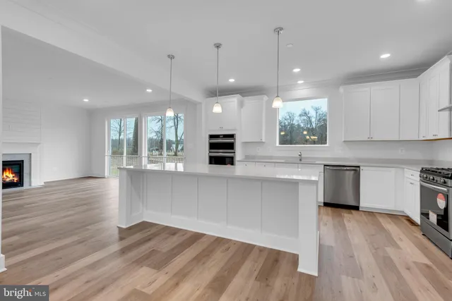 a open kitchen with white cabinets a stove a microwave and wooden floors