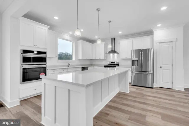 a kitchen with stainless steel appliances kitchen island a refrigerator sink and cabinets