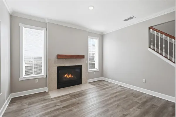 a view of an empty room with wooden floor fireplace and a window