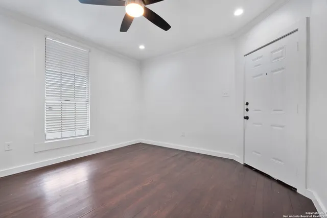 an empty room with wooden floor fan and windows