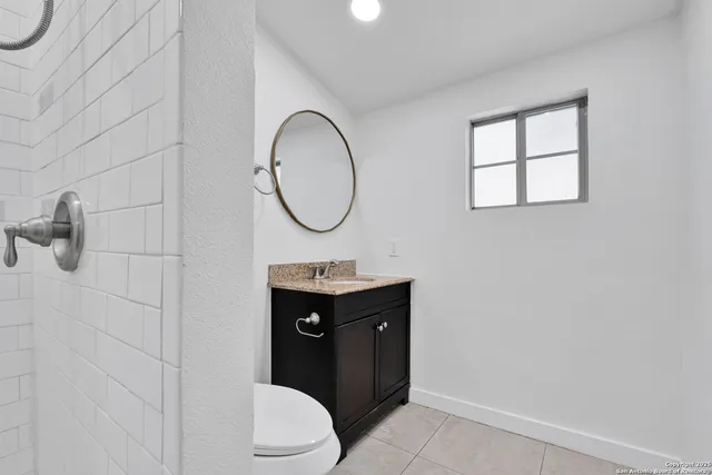 a bathroom with a toilet sink vanity and mirror