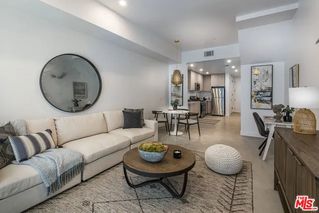 a living room with furniture a table and kitchen view
