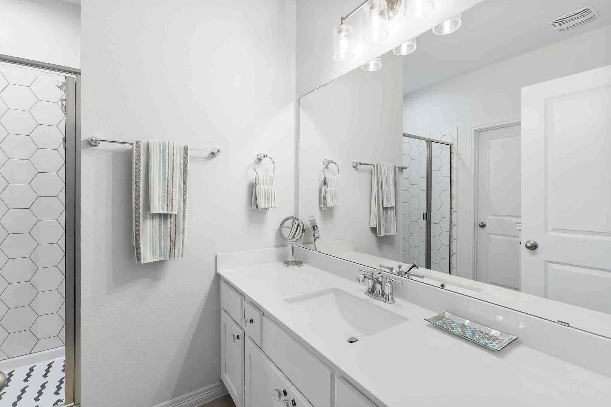 166 West Branch Road Kyle, TX 78640 - Photo 32 of 39 White walls and a large mirror enhance this bathroom's bright, clean aesthetic.