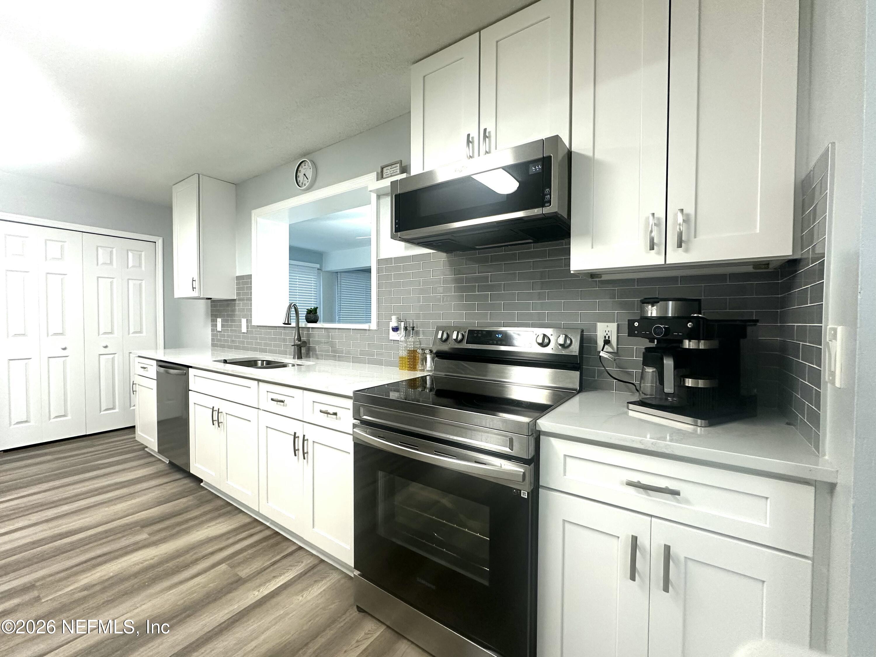 1516 Derringer Road Jacksonville, FL 32225 - Photo 24 of 55 a kitchen with stainless steel appliances white cabinets and a stove top oven