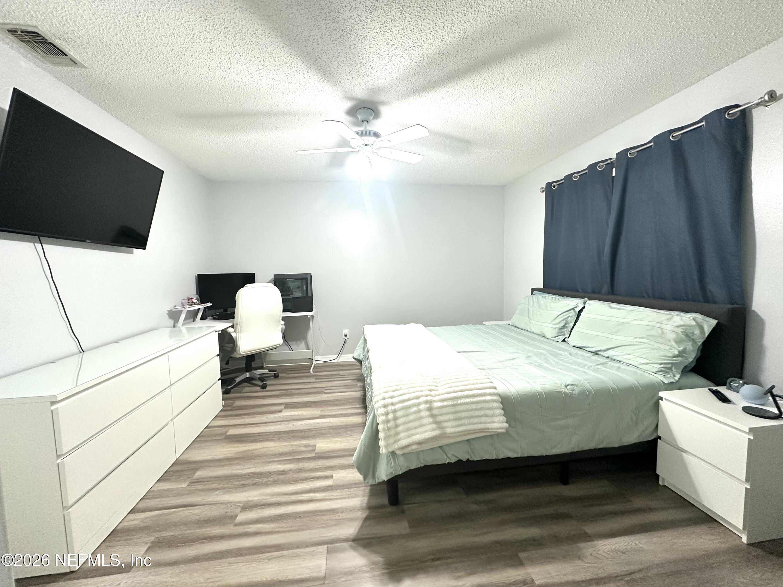 1516 Derringer Road Jacksonville, FL 32225 - Photo 42 of 55 a bedroom with a bed wooden floor and flat screen tv