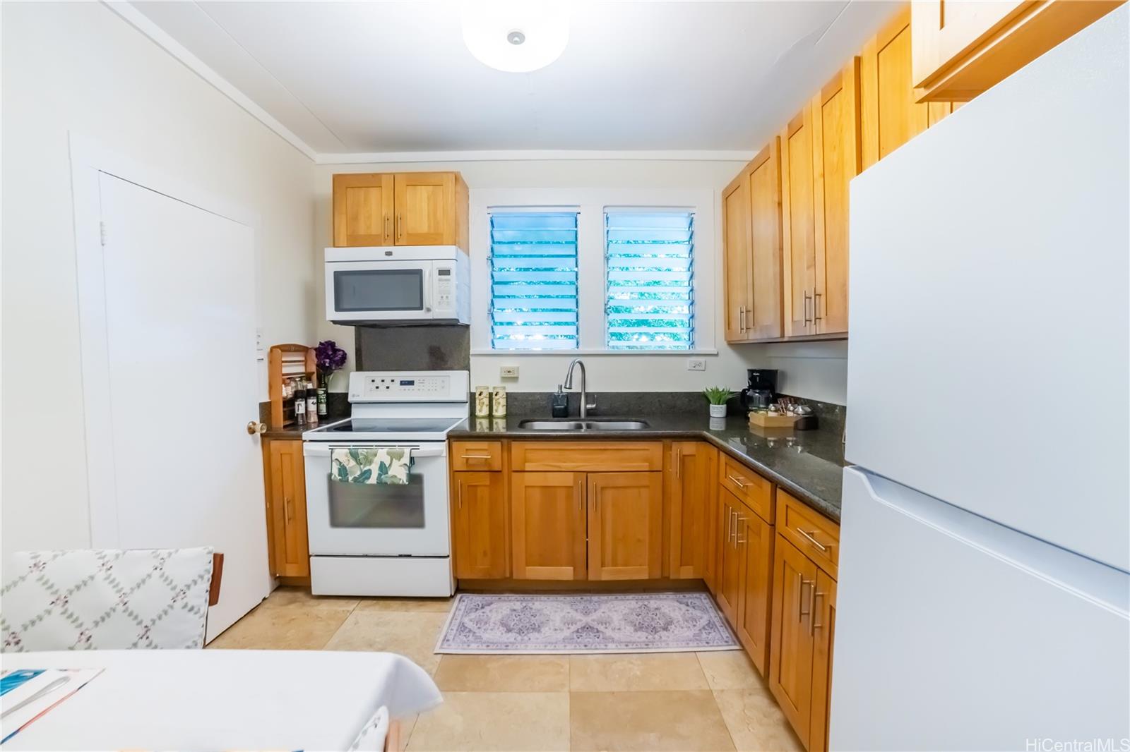 303 Wai Nani Way Honolulu, HI 96815 - Photo 16 of 24 a kitchen with granite countertop a stove a sink and a microwave
