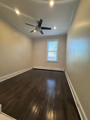 an empty room with wooden floor fan and windows