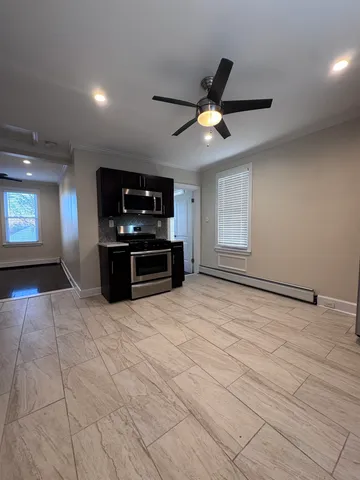 a view of an empty room with a kitchen and a window