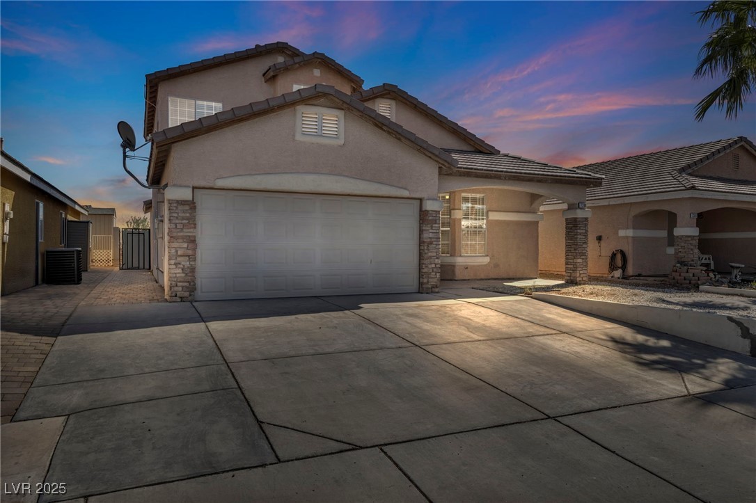 7308 Alpine Ridge Street Las Vegas, NV 89131 - Photo 1 of 47 View of front of property featuring an attached garage, stone siding, concrete driveway, a gate, and stucco siding