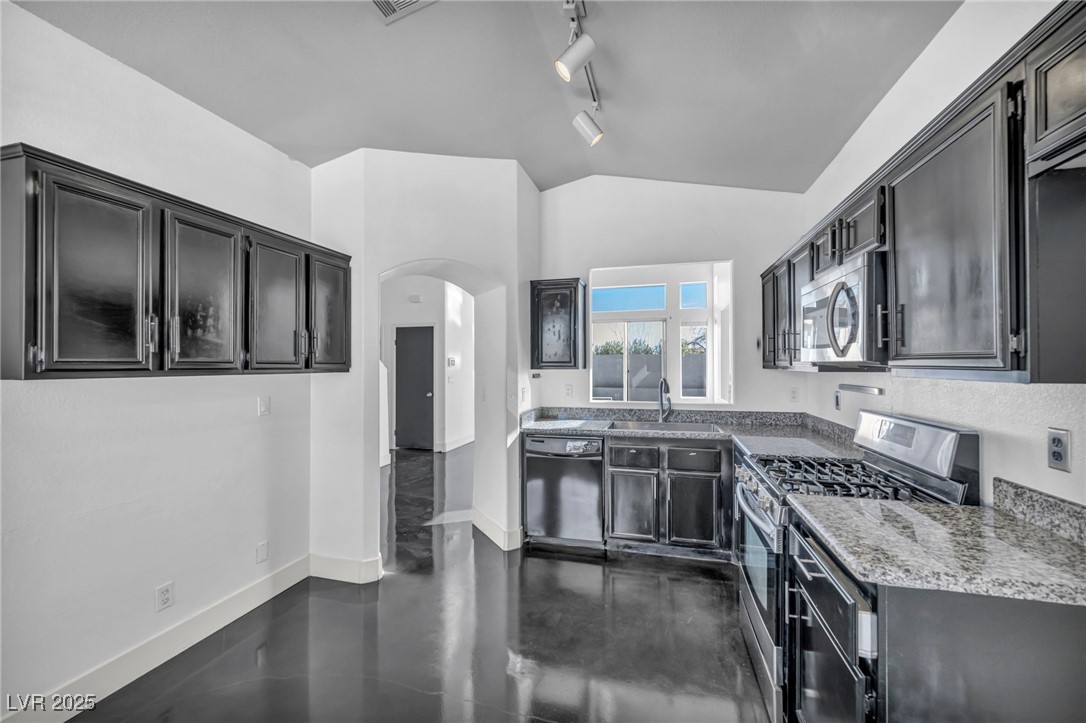 7308 Alpine Ridge Street Las Vegas, NV 89131 - Photo 11 of 47 Kitchen with baseboards, arched walkways, lofted ceiling, stainless steel appliances, and a sink