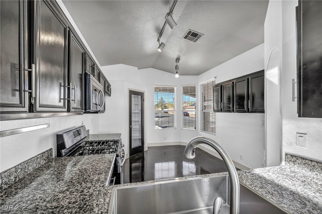 7308 Alpine Ridge Street Las Vegas, NV 89131 - Photo 12 of 47 Kitchen with visible vents, lofted ceiling, stainless steel appliances, a textured ceiling, and a sink