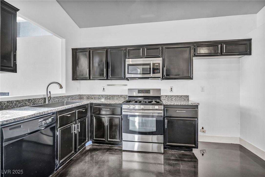 7308 Alpine Ridge Street Las Vegas, NV 89131 - Photo 13 of 47 Kitchen with stainless steel appliances, light countertops, a sink, dark cabinets, and concrete flooring