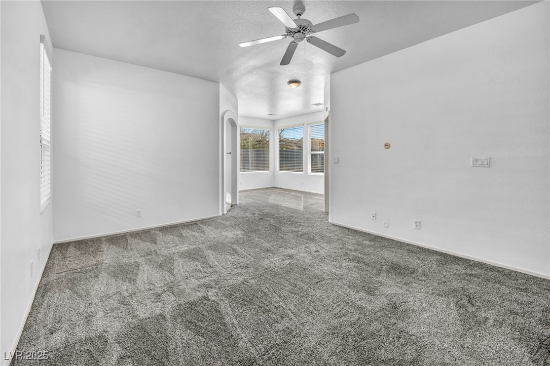 7308 Alpine Ridge Street Las Vegas, NV 89131 - Photo 17 of 47 Empty room with ceiling fan, arched walkways, carpet flooring, and baseboards