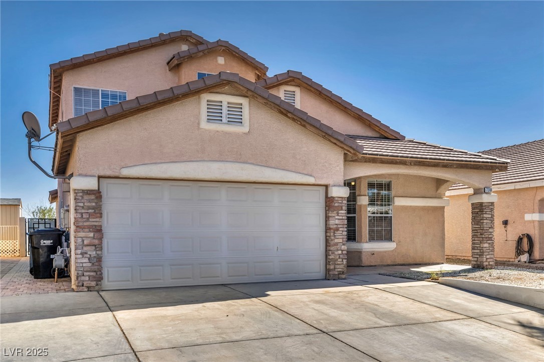 7308 Alpine Ridge Street Las Vegas, NV 89131 - Photo 2 of 47 Mediterranean / spanish-style home with a garage, stone siding, concrete driveway, and stucco siding