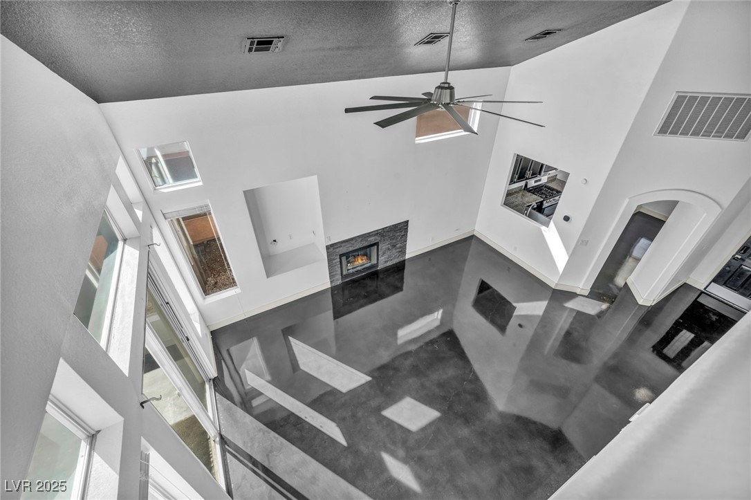 7308 Alpine Ridge Street Las Vegas, NV 89131 - Photo 29 of 47 Living room with high vaulted ceiling, visible vents, and a stone fireplace