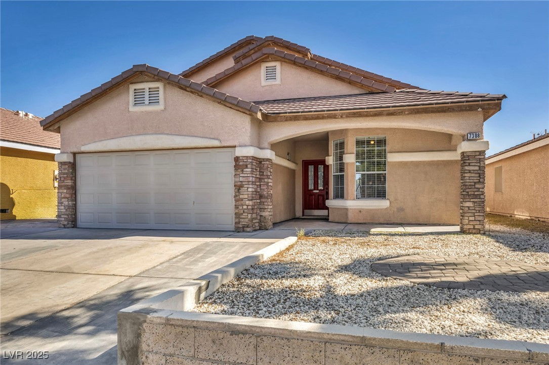 7308 Alpine Ridge Street Las Vegas, NV 89131 - Photo 3 of 47 View of front facade featuring a garage, a tiled roof, concrete driveway, and stucco siding