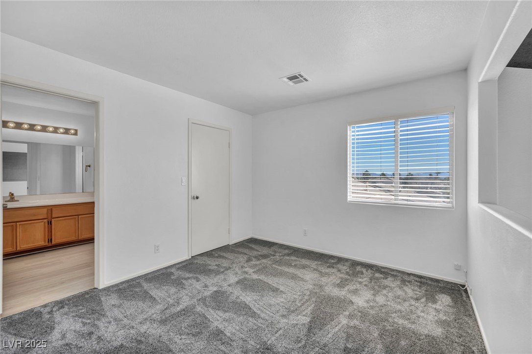 7308 Alpine Ridge Street Las Vegas, NV 89131 - Photo 31 of 47 Unfurnished bedroom featuring carpet floors, connected bathroom, visible vents, and a sink