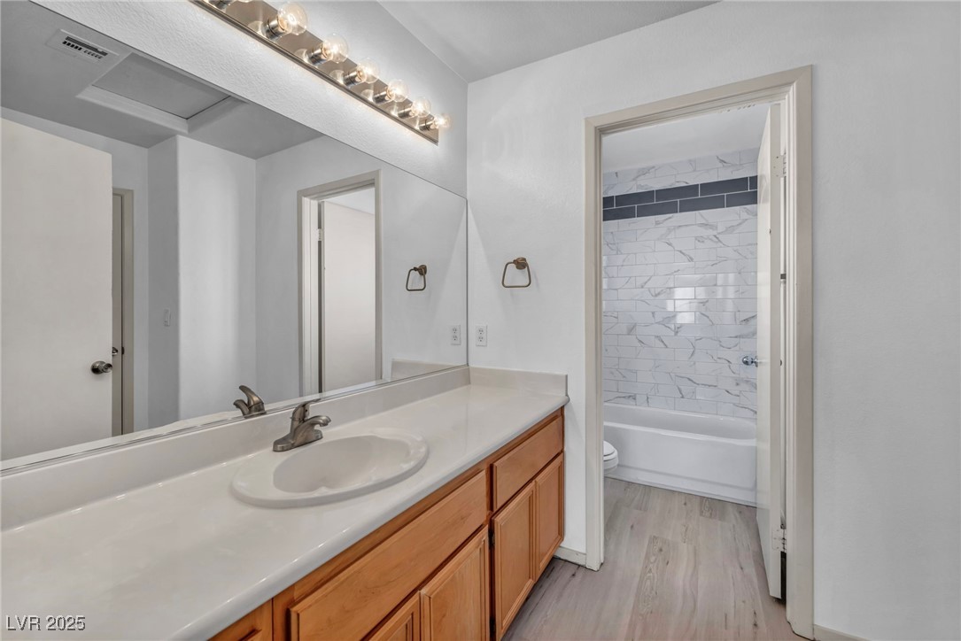 7308 Alpine Ridge Street Las Vegas, NV 89131 - Photo 32 of 47 Bathroom featuring visible vents, toilet, vanity, shower / tub combination, and wood finished floors