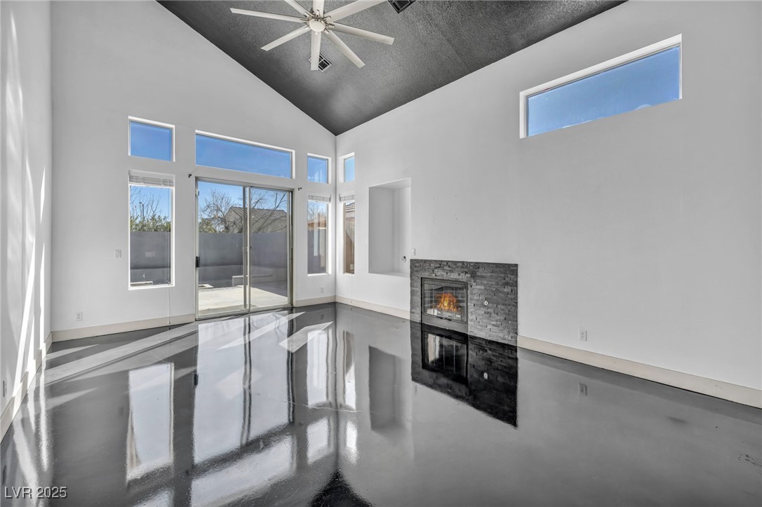 7308 Alpine Ridge Street Las Vegas, NV 89131 - Photo 6 of 47 Living room with high vaulted ceiling, a fireplace, a wealth of natural light, and finished concrete floors