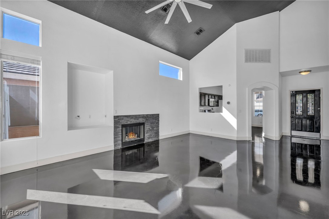 7308 Alpine Ridge Street Las Vegas, NV 89131 - Photo 9 of 47 Living area with high vaulted ceiling, visible vents, a fireplace, and finished concrete flooring