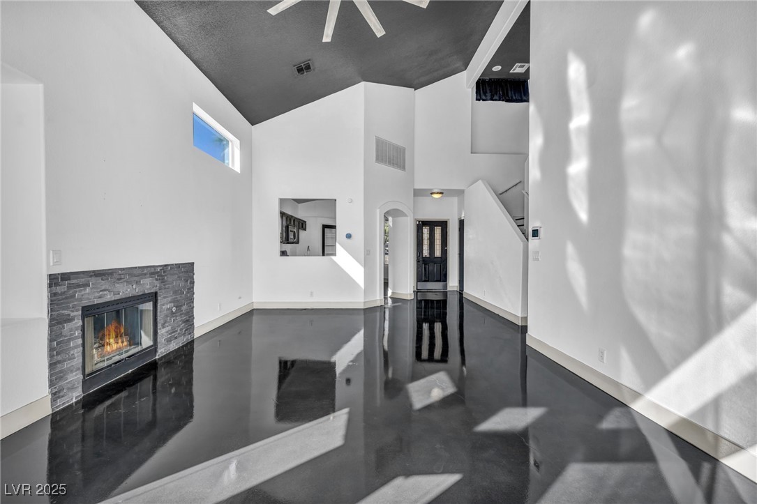 7308 Alpine Ridge Street Las Vegas, NV 89131 - Photo 10 of 47 Living room featuring visible vents, a towering ceiling, stairway, concrete flooring, and a stone fireplace