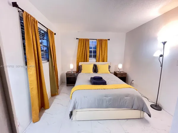 a bedroom with a bed and a large mirror next to a window