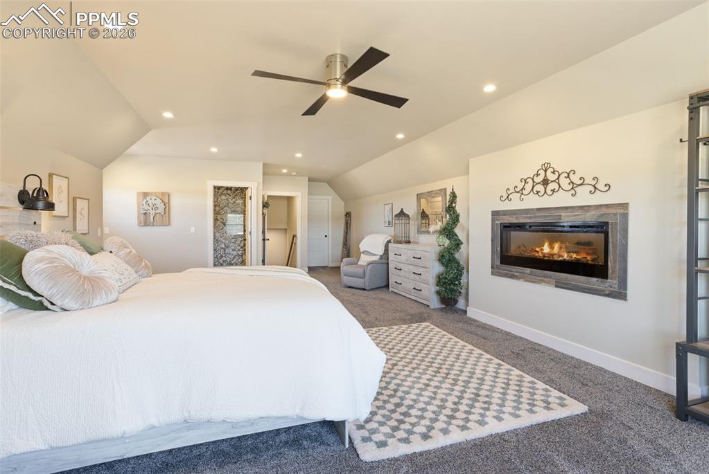16835 Goshawk Road Colorado Springs, CO 80908 - Photo 29 of 50 a spacious bedroom with a bed a mirror and a flat screen tv