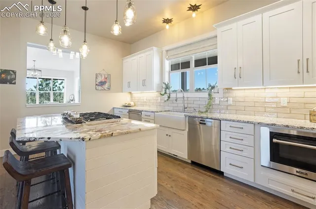 a kitchen that has a sink a stove and chairs