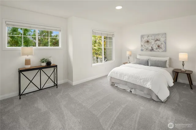 a bedroom with a bed a table and painting next to a window