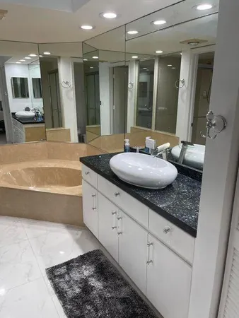 a bathroom with a granite countertop double vanity sink large mirror and tub