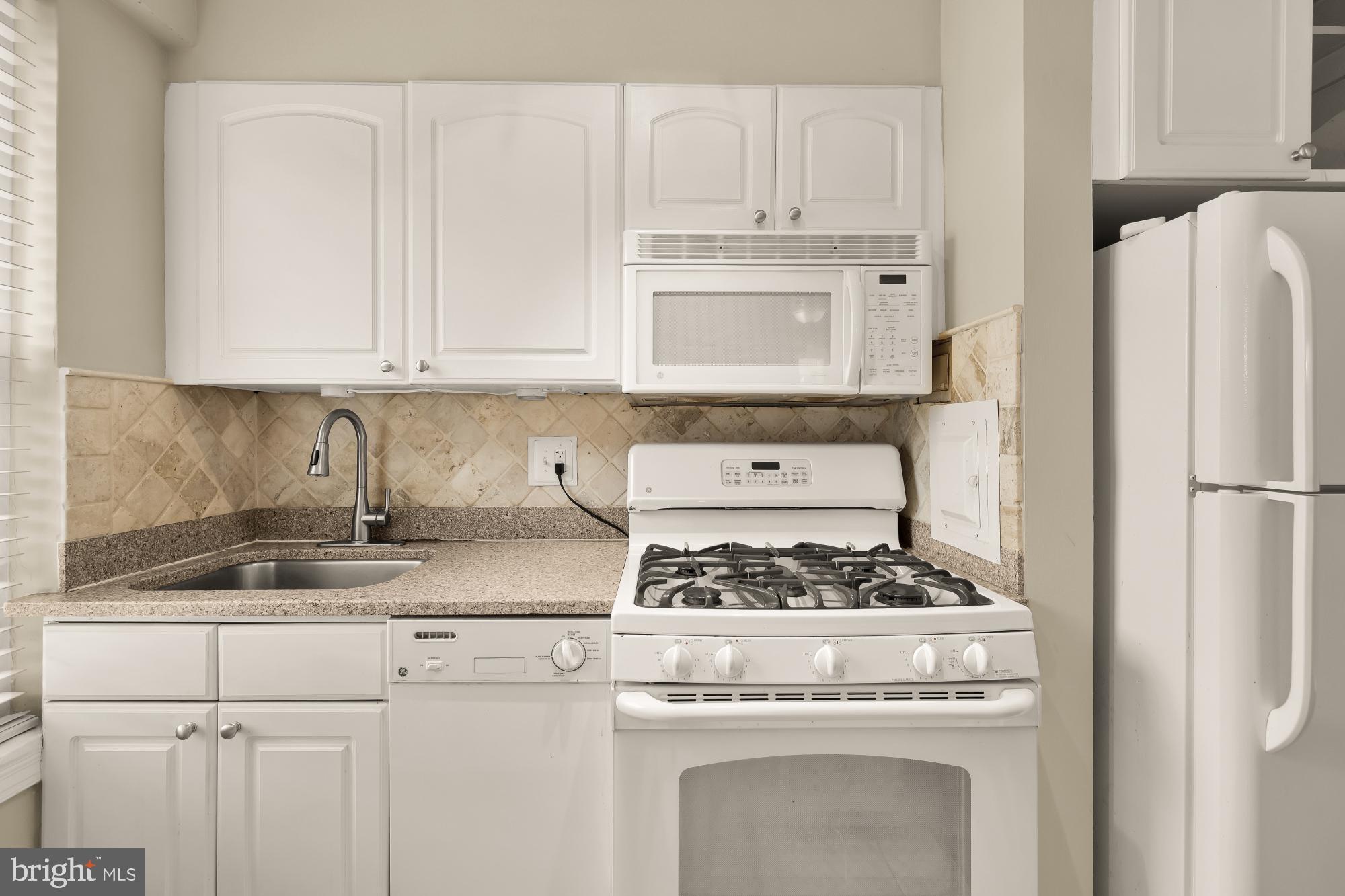 2130 N Street Northwest, Unit 407 Washington, DC 20037 - Photo 23 of 31 a kitchen with granite countertop white cabinets and refrigerator