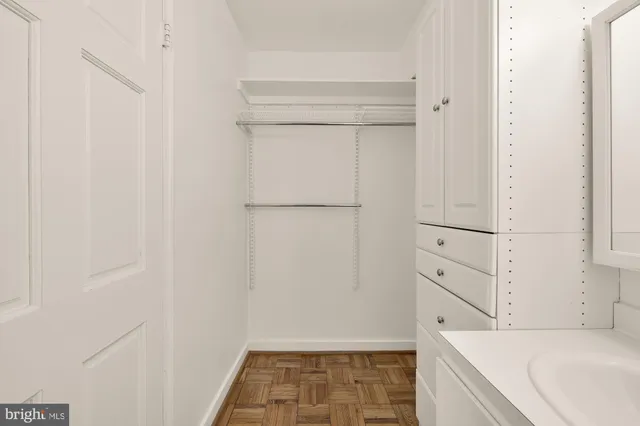 a utility room with stainless steel appliances wooden floors and white cabinets