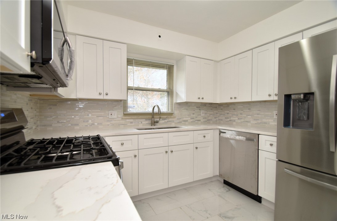 3681 Brinkmore Road Cleveland Heights, OH 44121 - Photo 11 of 27 Kitchen featuring light tile flooring, white cabinets, appliances with stainless steel finishes, and tasteful backsplash