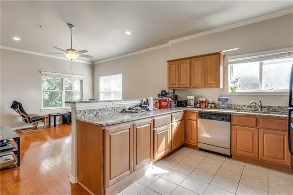 a kitchen with stainless steel appliances granite countertop a stove top oven a sink dishwasher and white cabinets with wooden floor