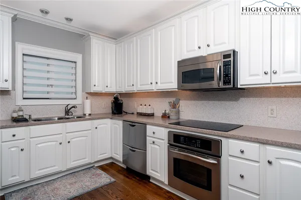 a kitchen with granite countertop white cabinets and stainless steel appliances