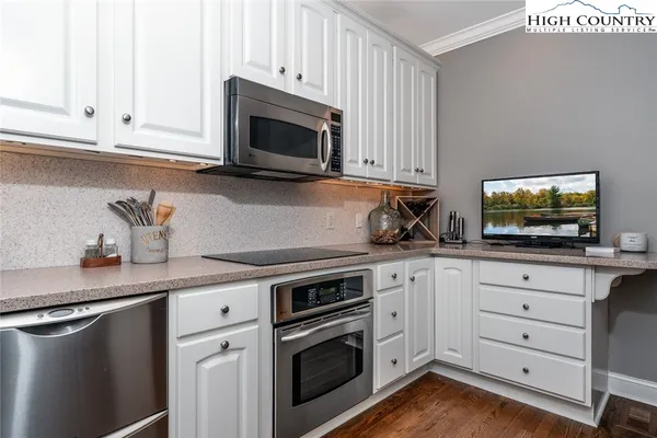 a kitchen with white cabinets and a stove with wooden floor