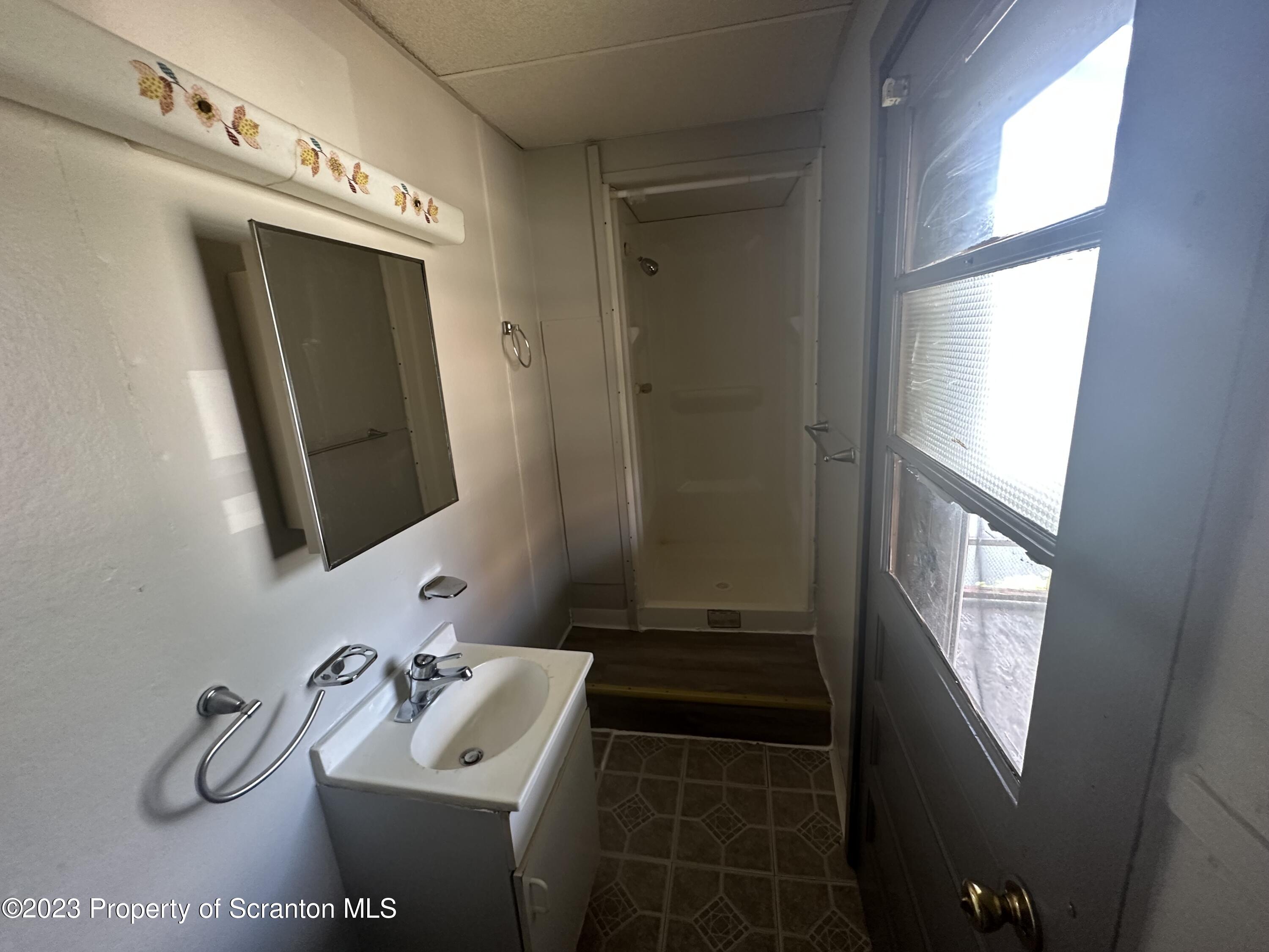 130 State Street, Unit ST Nanticoke, PA 18634 - Photo 7 of 8 a bathroom with a sink a toilet a mirror and window