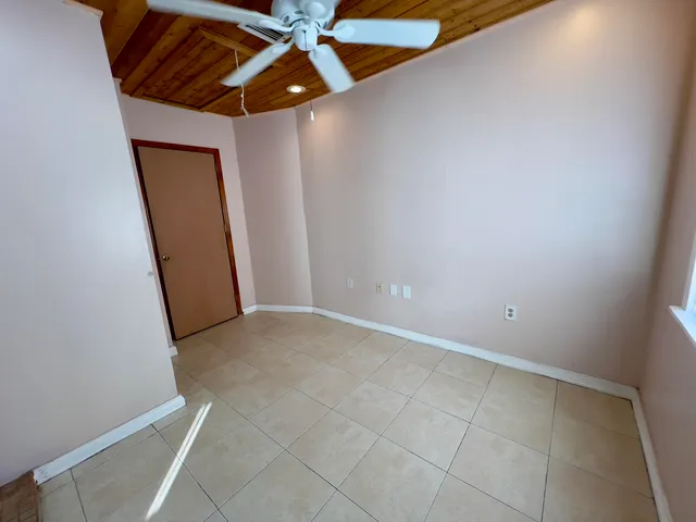 an empty room with a mirror and a ceiling fan