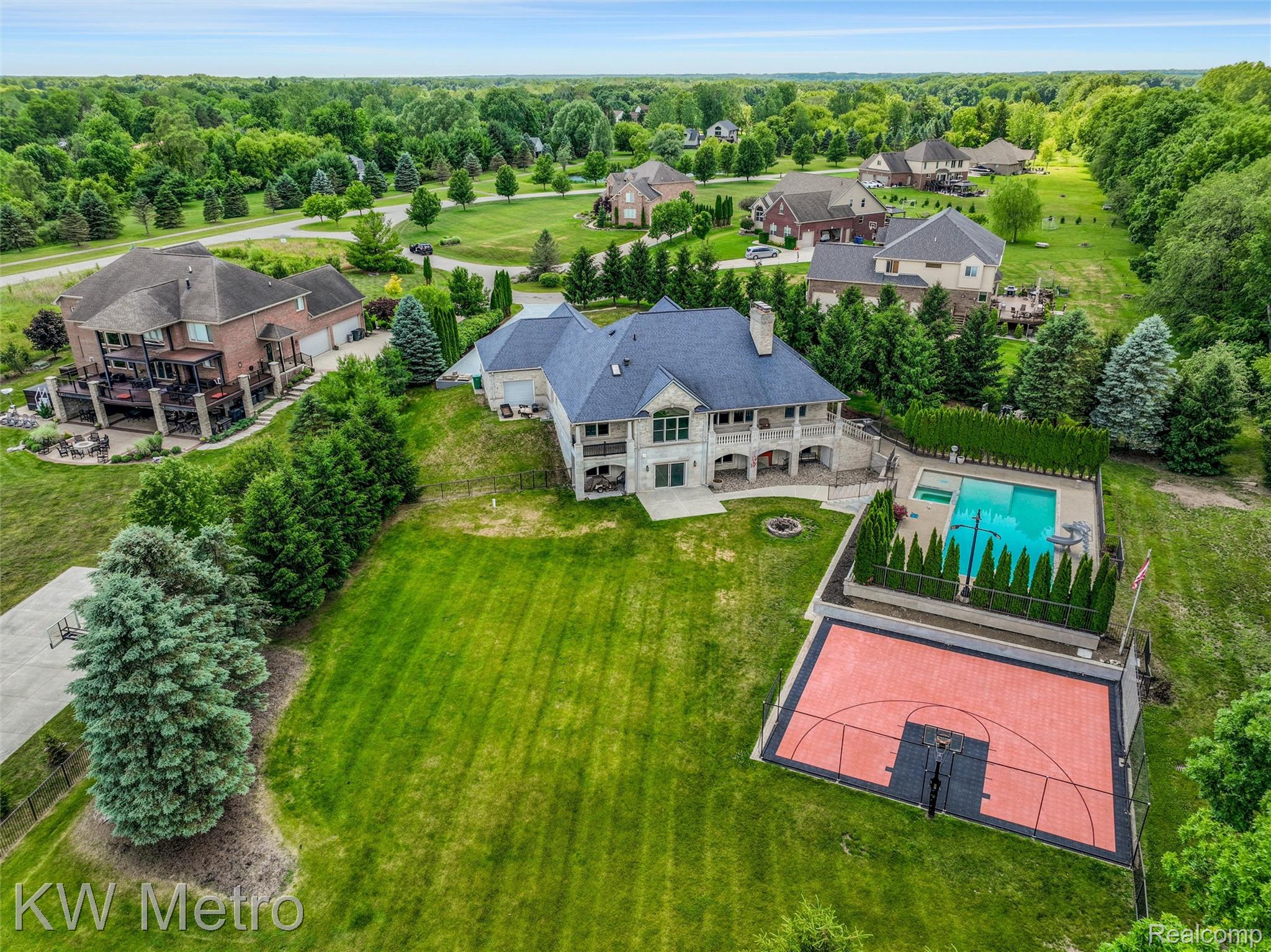 65884 Windrose Court Ray, MI 48096 - Photo 23 of 82 Expansive property featuring a large residence with a multi-level deck, a swimming pool with an integrated spa, and a dedicated sports court