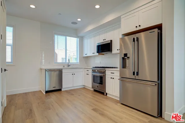 a kitchen with a refrigerator stove and wooden floor