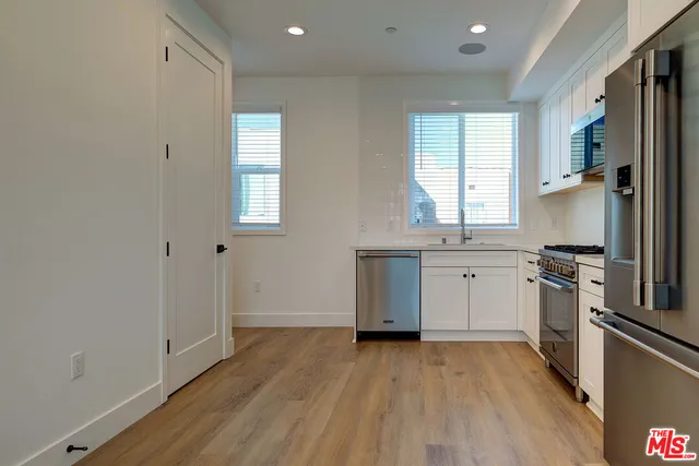 a kitchen with a sink wooden floor and stainless steel appliances