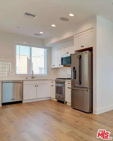a kitchen with granite countertop a refrigerator and a stove top oven