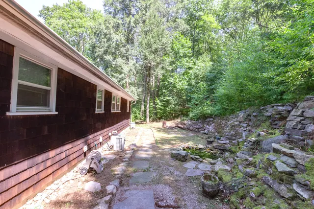 a backyard of a house with large trees and outdoor seating