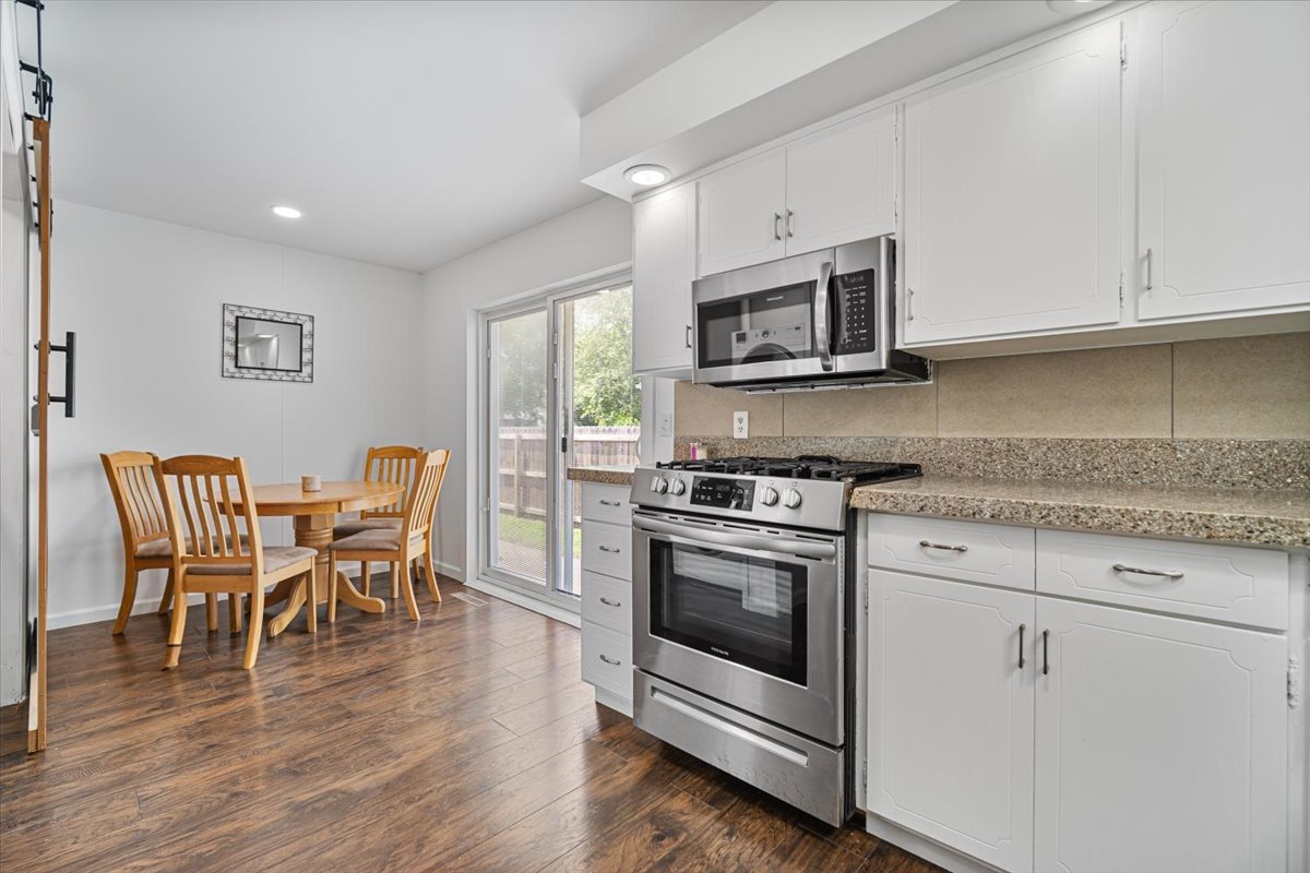 396 North Sherman Street El Paso, IL 61738 - Photo 9 of 29 a kitchen with stainless steel appliances granite countertop a stove a microwave a dining table and chairs with wooden floor