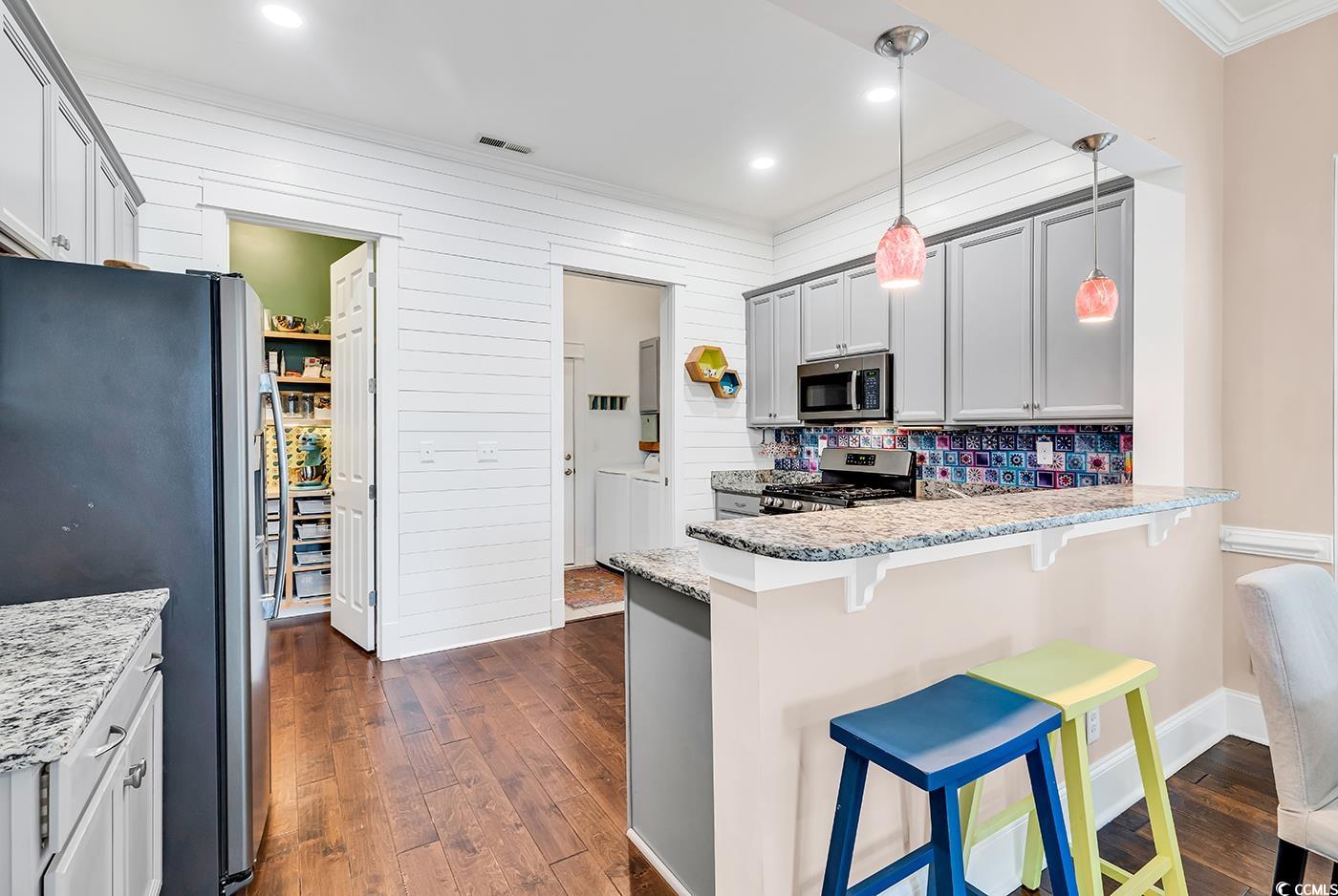1411 Peterson Street Myrtle Beach, SC 29577 - Photo 6 of 40 Kitchen with ornamental molding, pendant lighting, appliances with stainless steel finishes, a breakfast bar, and light stone countertops